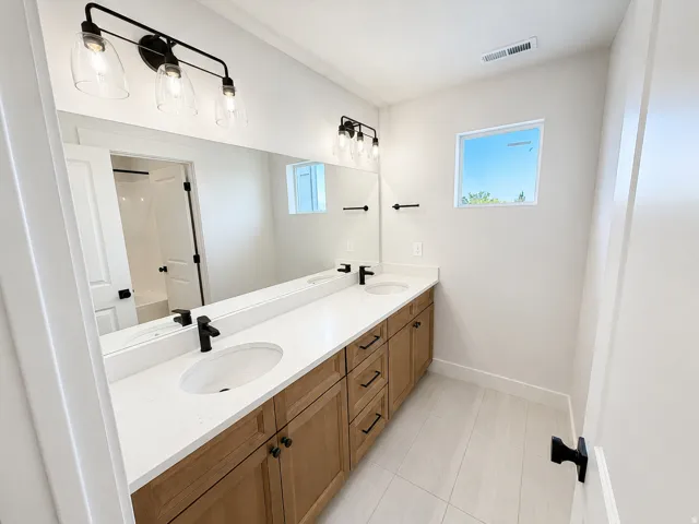 Dual vanity with undermount sinks, white countertops, and wood-finish cabinetry
