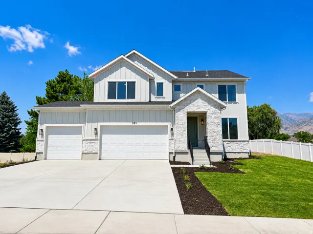 Modern exterior with vertical siding and stone accents, a multi-car driveway, attached garage, and a landscaped front yard