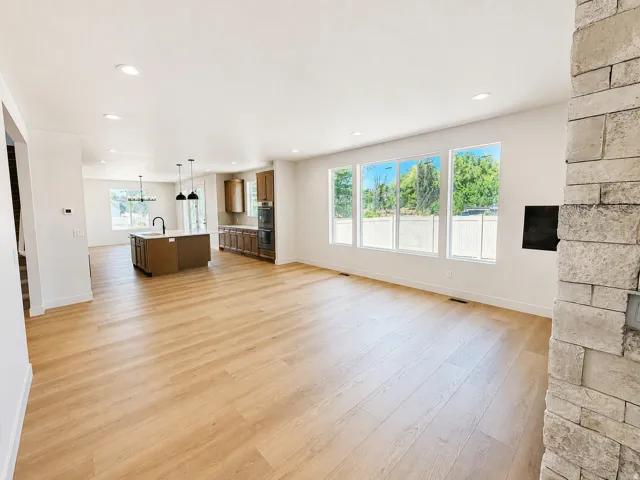 Spacious main living area featuring wood-finish flooring, a stone accent wall, recessed lighting, and multiple windows