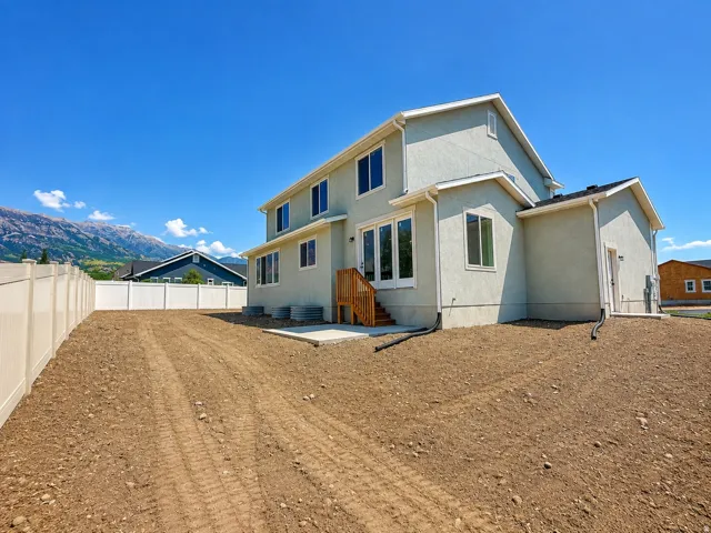 Stucco exterior with multiple windows, leading to a wooden deck