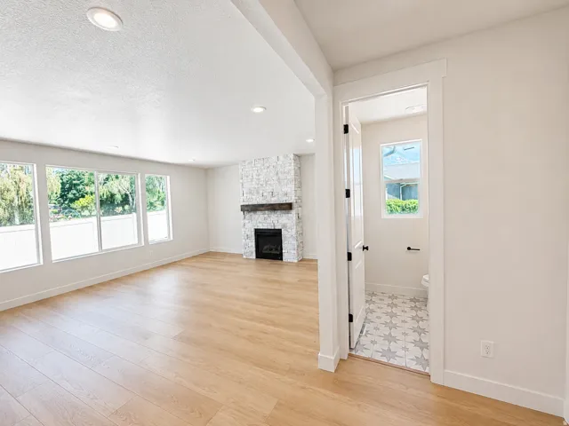 Recessed ceiling lighting, wood-finish flooring, and a stone-clad fireplace with a wood mantle