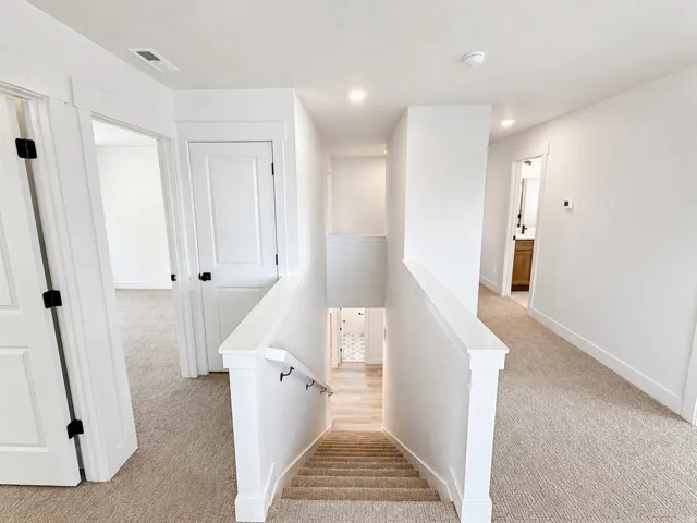Upper-level landing with neutral tone carpeting and crisp white walls