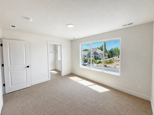 White interior walls, recessed lighting, wall-to-wall carpeting, white interior doors with black hardware, and a window with white trim