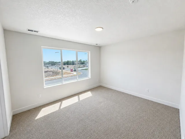 White textured wall-to-wall carpeting, white walls, large window with white trim, recessed ceiling lighting
