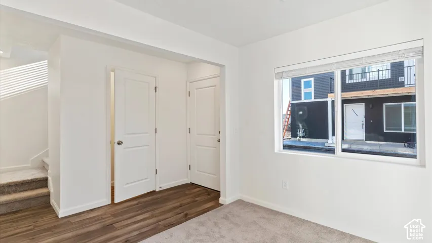 White wall paint, wood-finish flooring, two-panel interior doors, and a window with blinds