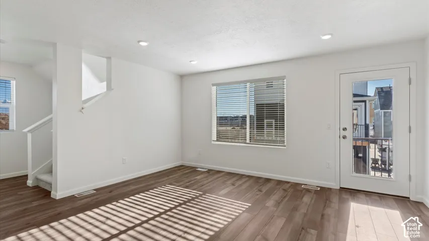 Wood-finish flooring, recessed lighting, and a full-light exterior door with a balcony