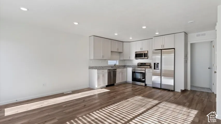Kitchen featuring light-toned cabinetry, stainless steel appliances, and a solid surface countertop