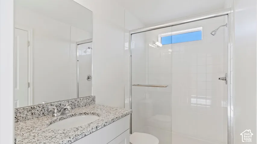 White vanity with a speckled countertop, undermount sink, and chrome faucet