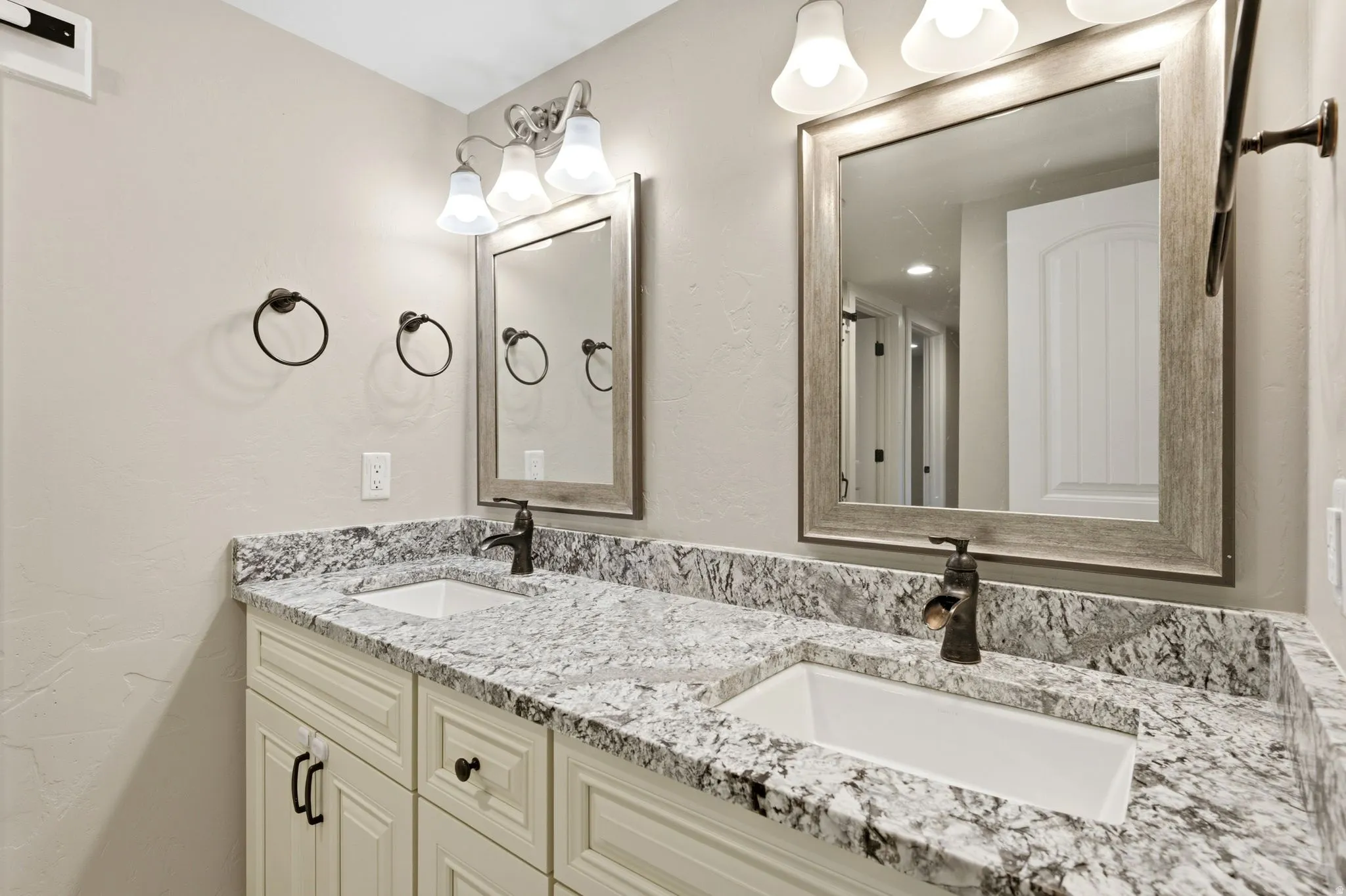 Dual vanity with granite countertops, undermount sinks, and bronze-finish faucets