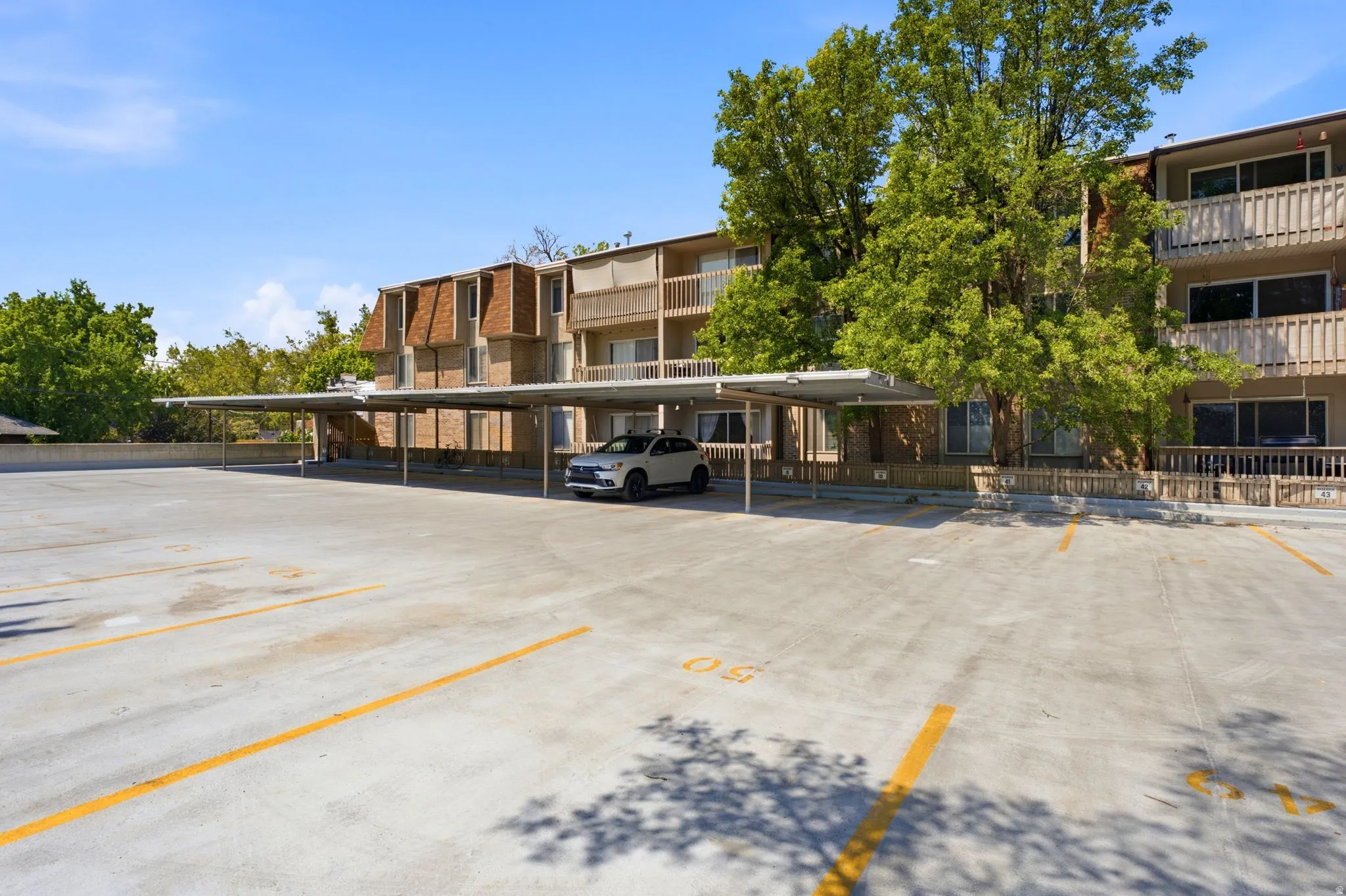 Designated covered parking spaces, open surface parking, and multi-story building exterior with balconies