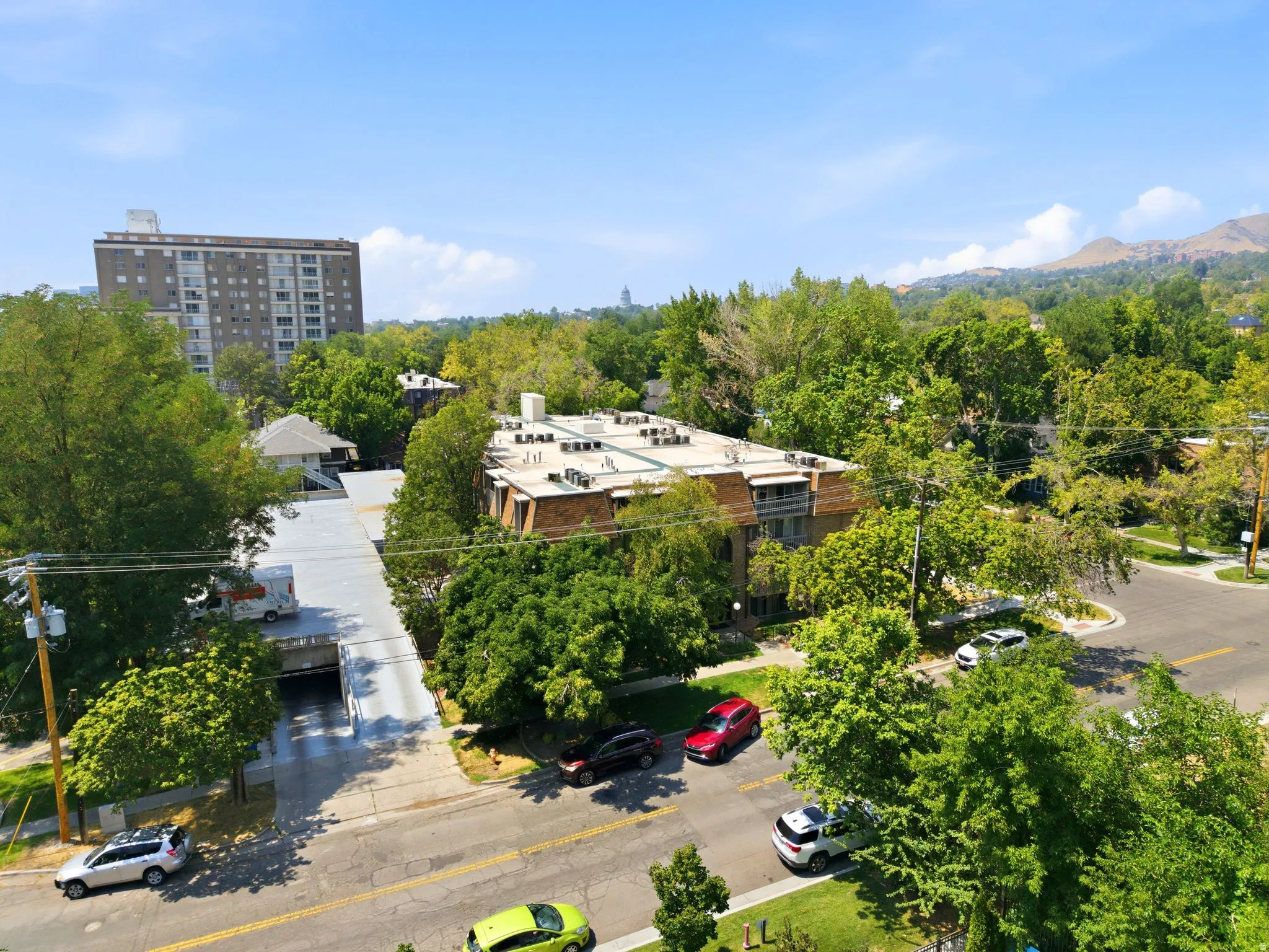 Multi-story building with a flat roof, surrounded by mature trees