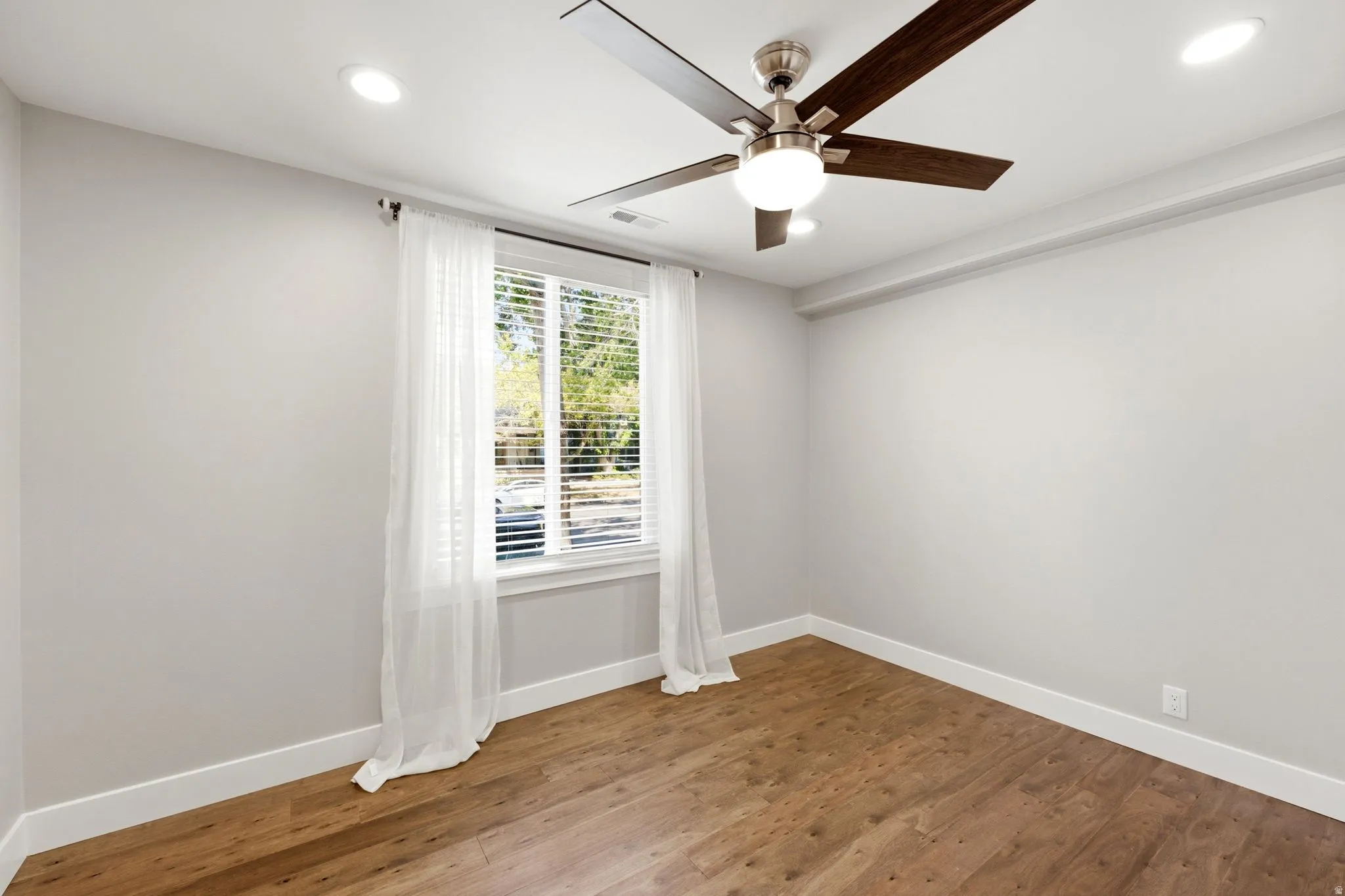 Recessed ceiling lighting, wood-finish flooring, ceiling fan with integrated light, window with blinds, and white trim