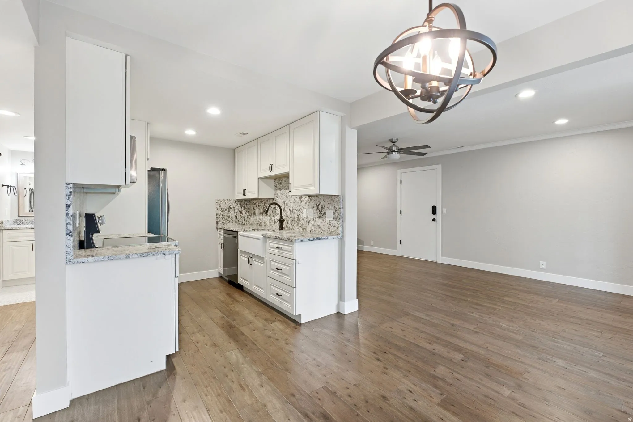 Open concept living space featuring wood-finish flooring, recessed lighting, and a modern orb chandelier