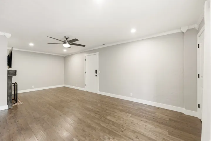 Spacious room with wood-finish flooring, recessed lighting, ceiling fan, and a fireplace with brick hearth