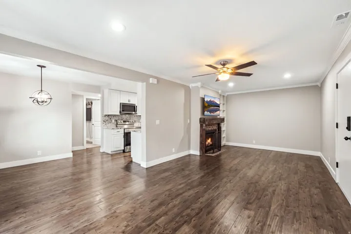 Wood-finish flooring throughout, recessed lighting, and a corner fireplace with built-in shelving