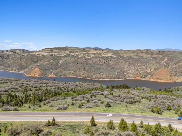 Expansive water body bordered by sloping hillsides, featuring natural vegetation and a multi-lane roadway
