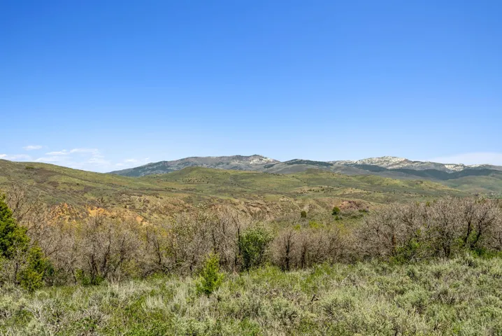 Expansive natural landscape with varied terrain, featuring distant mountain ranges under a clear sky
