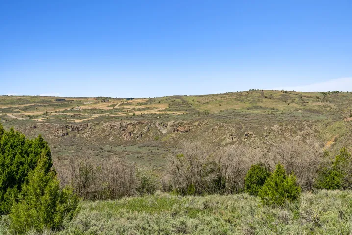 Expansive landscape featuring distant hills and a rugged cliff face