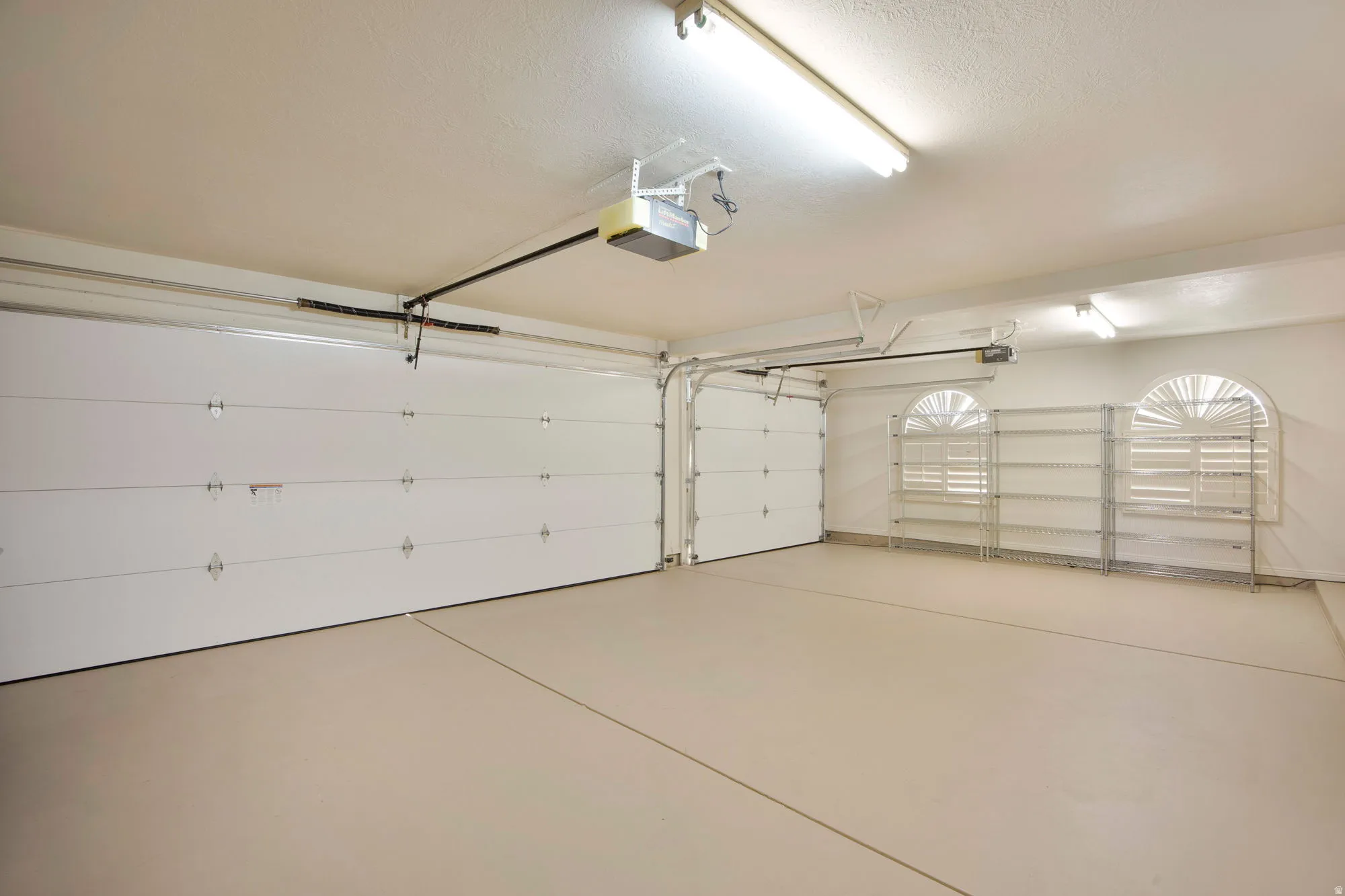 Two-car garage with two overhead doors, an automatic garage door opener, and arched window details
