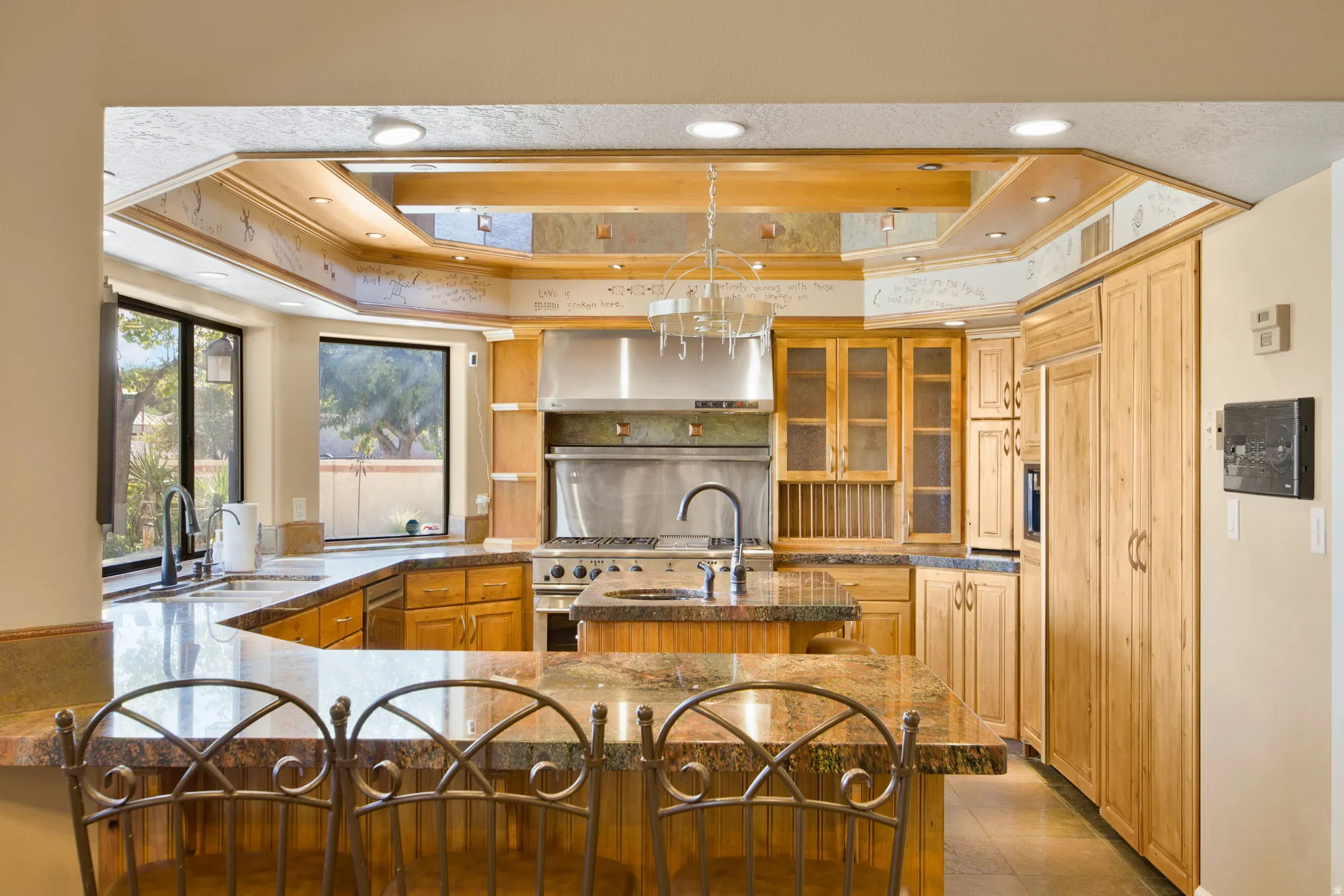 Kitchen featuring recessed lighting, natural wood cabinetry, stainless steel appliances, granite countertops, and a center island with a built-in sink