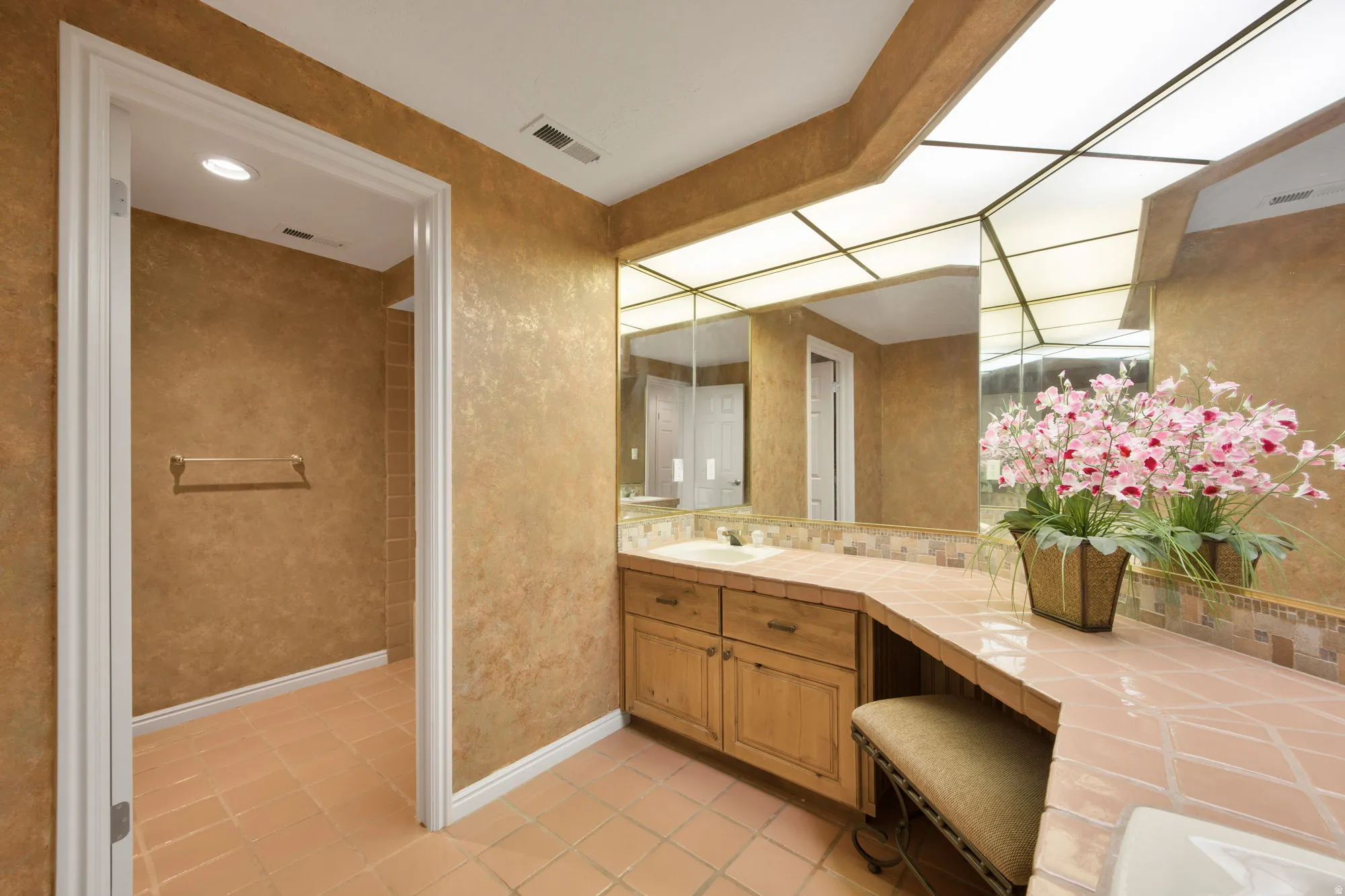 Spa-inspired primary bathroom featuring dual vanities with wood cabinetry, generous quartz countertops, and a frameless glass-enclosed walk-in shower with tile surround