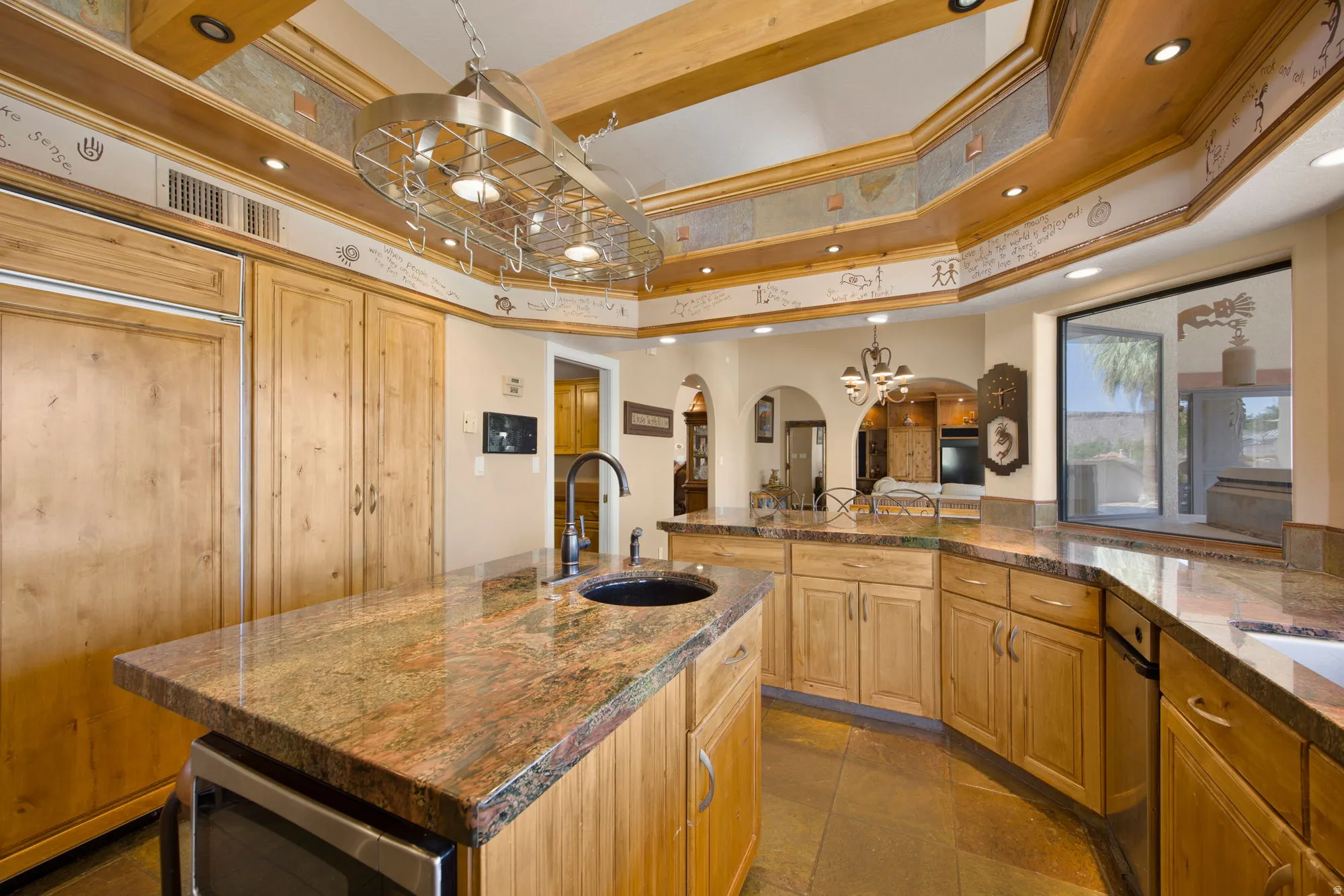 Kitchen featuring wood cabinetry, stone countertops, a central island with an integrated microwave, and a pot rack light fixture