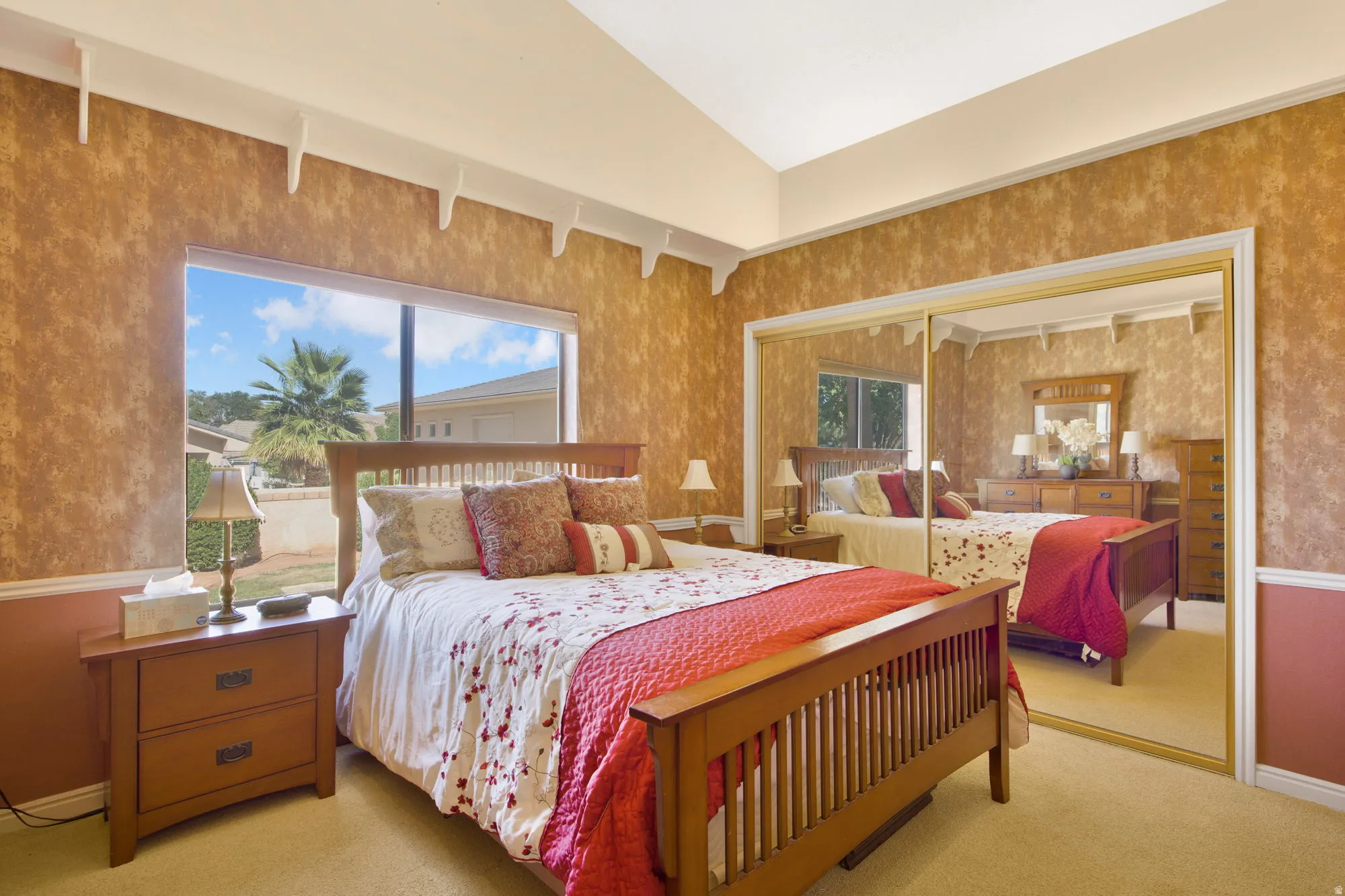 Vaulted ceiling with decorative corbels, large window, and mirrored sliding closet doors