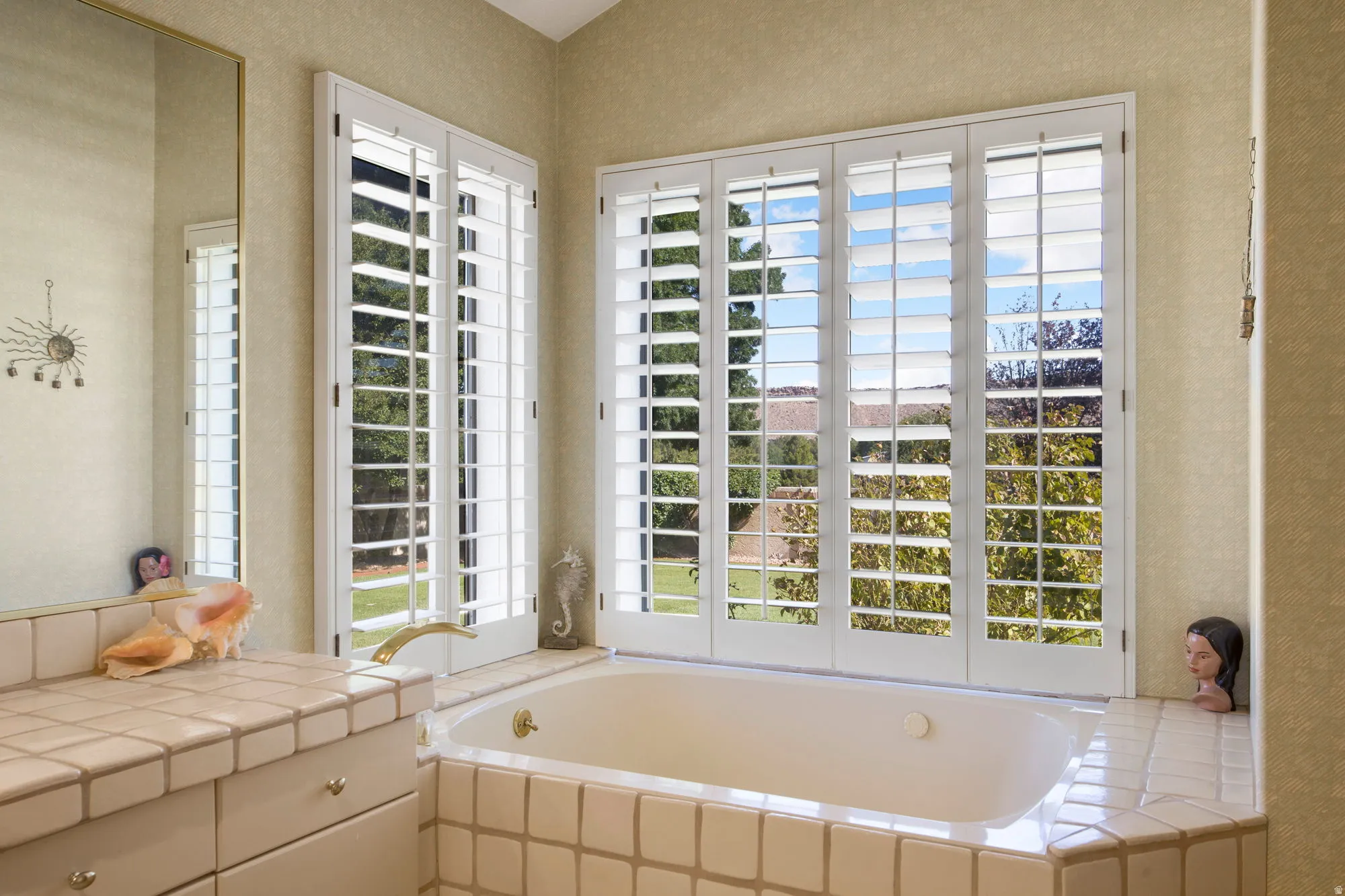 Built-in soaking tub with brass fixtures, surrounded by tiled decking