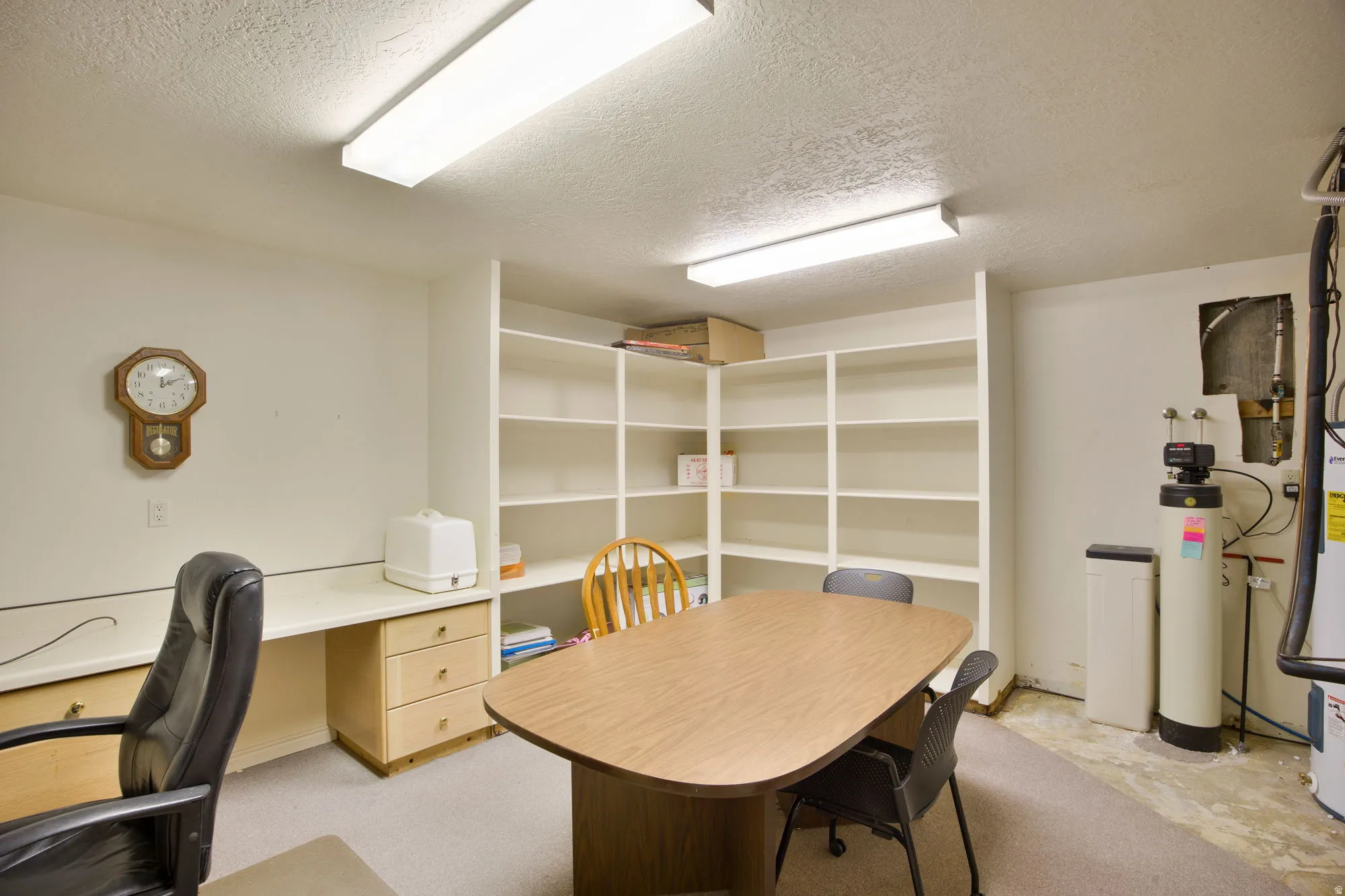 Built-in desk with light wood-finish drawers, integrated shelving, and fluorescent ceiling lighting