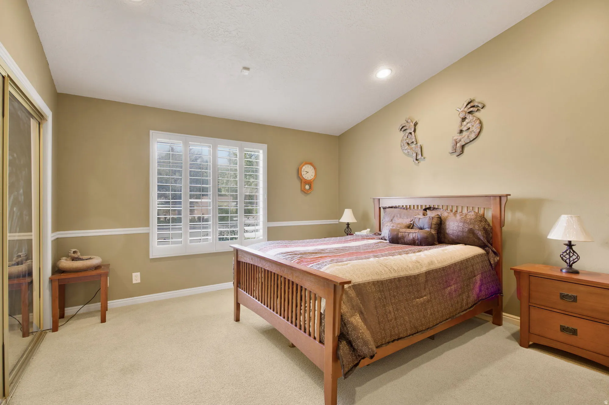 Recessed ceiling lighting, white crown molding, large window with plantation shutters, mirrored closet doors, and light-toned carpeting
