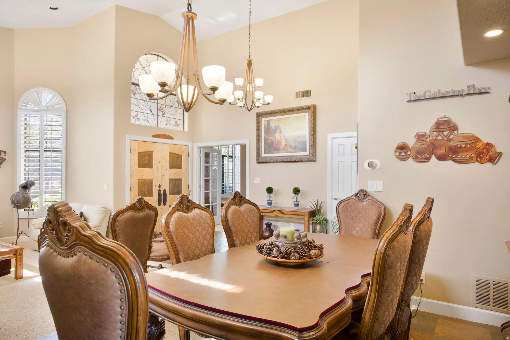 Elegant formal dining room showcasing a wood-finish table with upholstered seating, brushed brass pendant lighting, and soaring ceilings with crown molding