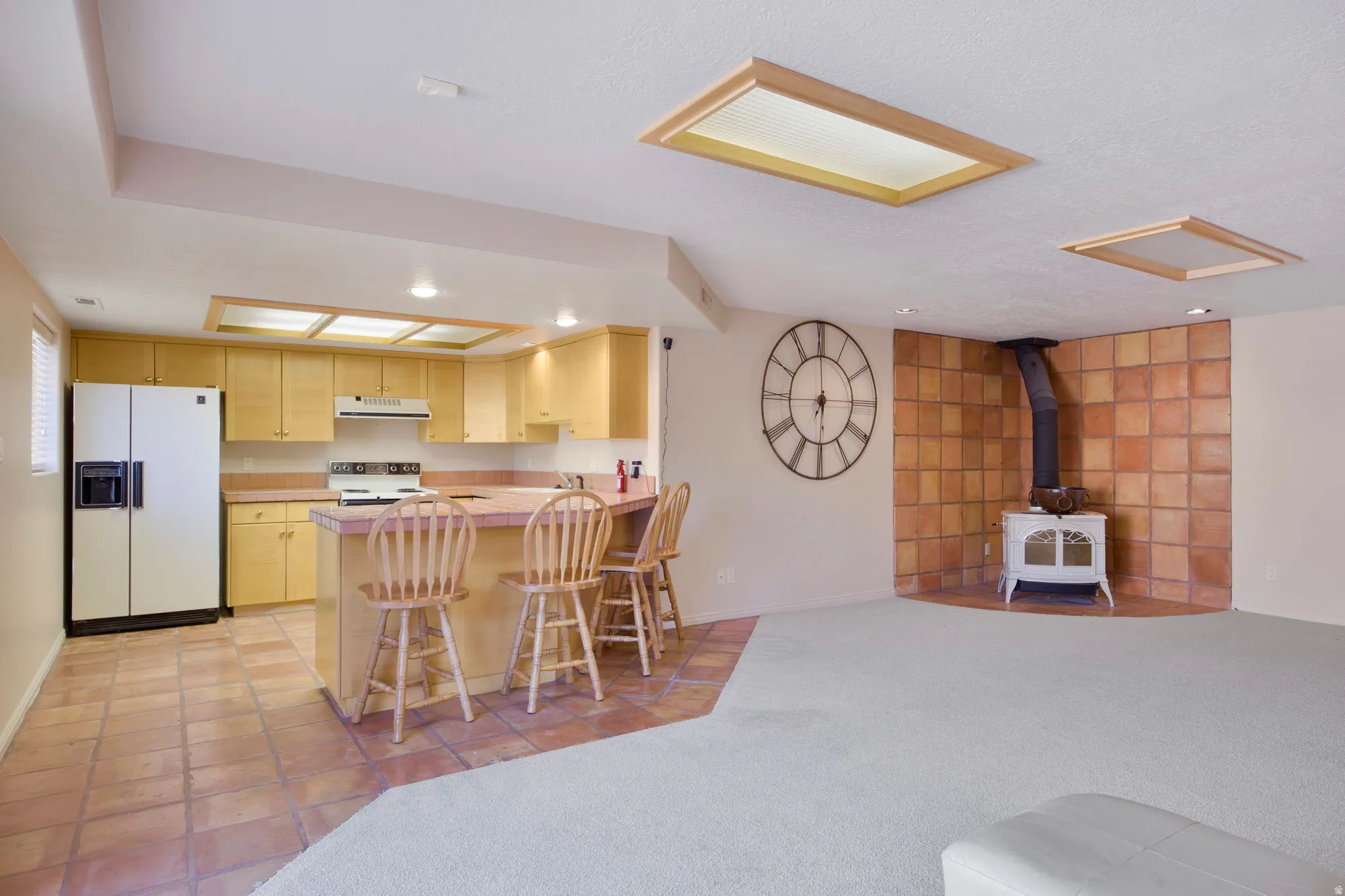 Kitchenette with wood-finish cabinetry, bar seating, and tile flooring