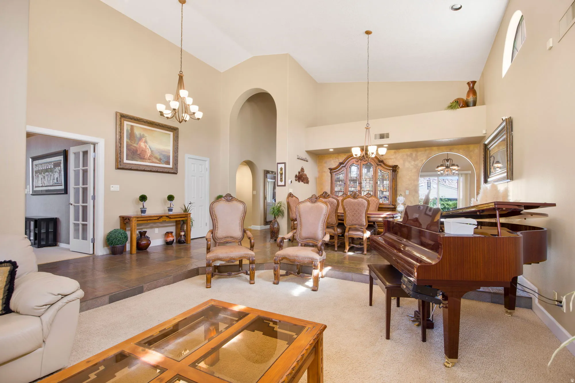 Vaulted ceilings, arched doorways, tiled flooring, French doors, and elevated architectural detailing