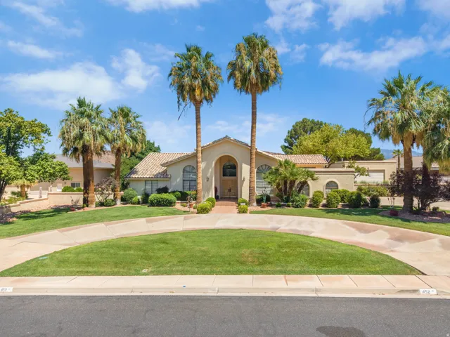 Stucco exterior with a tile roof, mature palm trees, and a circular drive