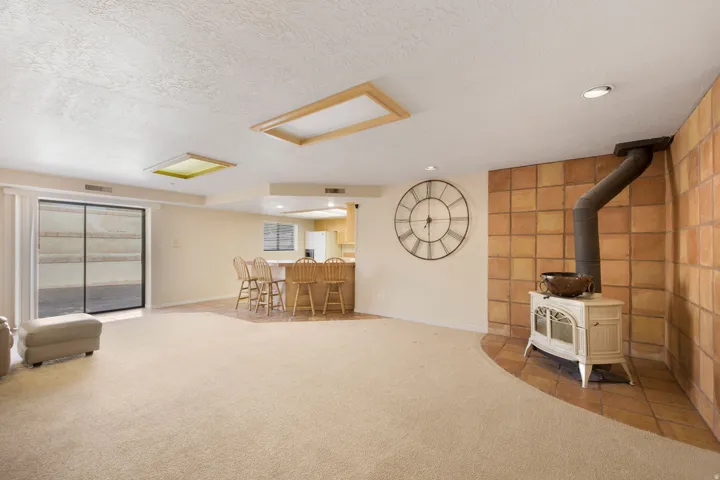 Spacious open-concept living area featuring neutral carpeting throughout, recessed ceiling lighting, and sliding glass doors with integrated blinds