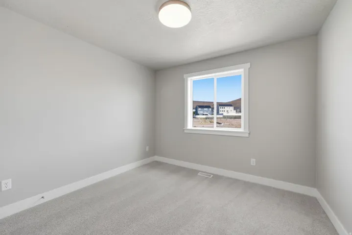 Neutral grey wall paint with white trim, light grey carpeting, and a white framed window