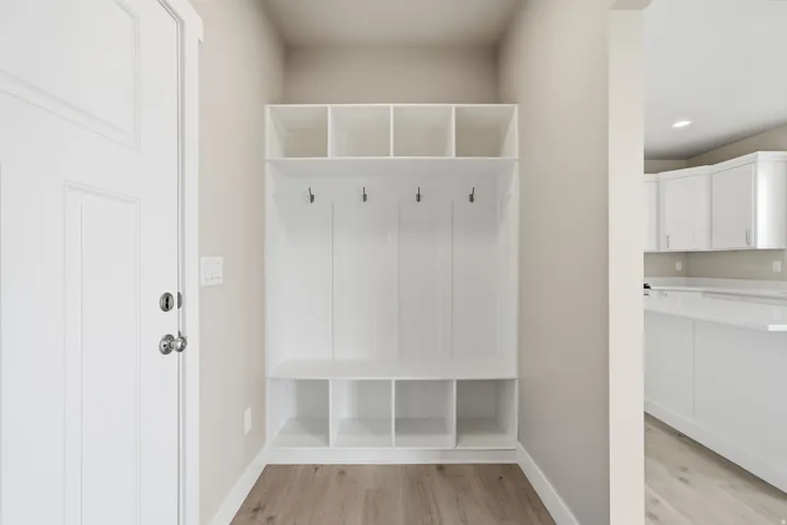Built-in storage bench with upper cubbies and coat hooks, wood-finish flooring, and a white paneled door