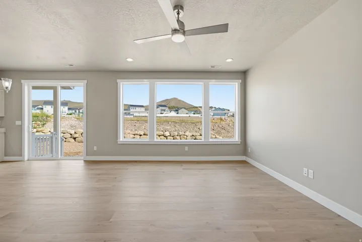 Recessed lighting, light wood-finish flooring, ceiling fan, multiple windows, and a sliding glass door