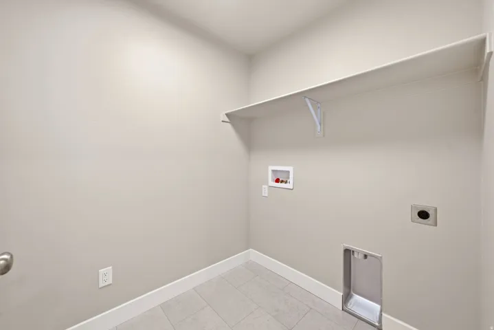 Utility room featuring a built-in shelf, plumbing hookups, electrical outlets, and tile flooring
