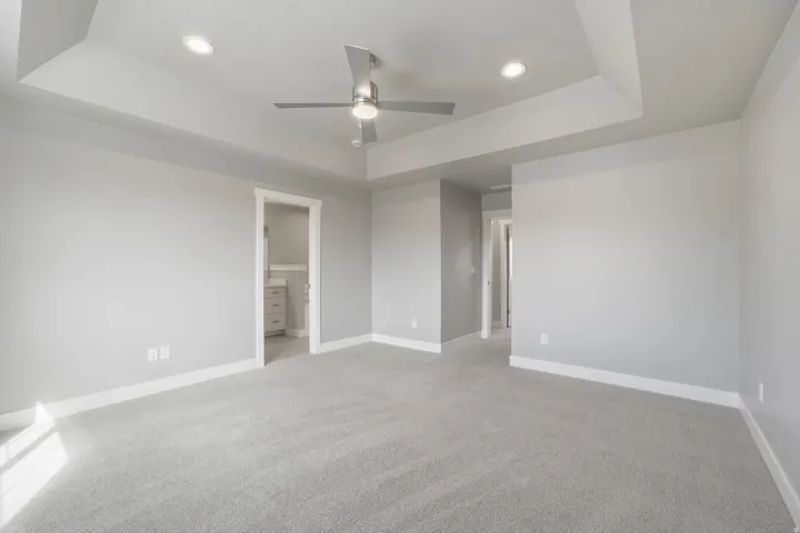 Recessed lighting, ceiling fan, tray ceiling, light gray carpeting, and light gray walls