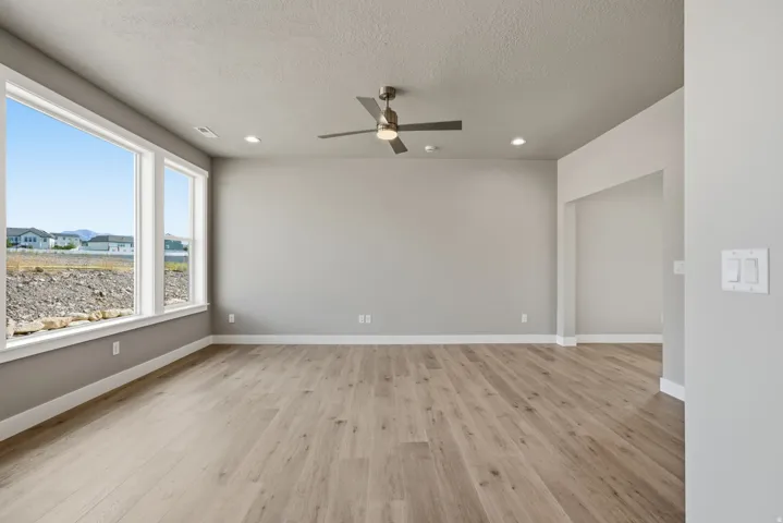 Expansive room with wood-finish flooring, recessed lighting, and a ceiling fan