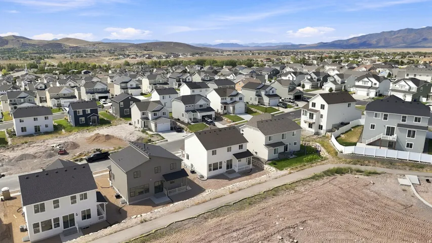 Expansive residential development with contemporary homes, varied exterior finishes, and mountain backdrops