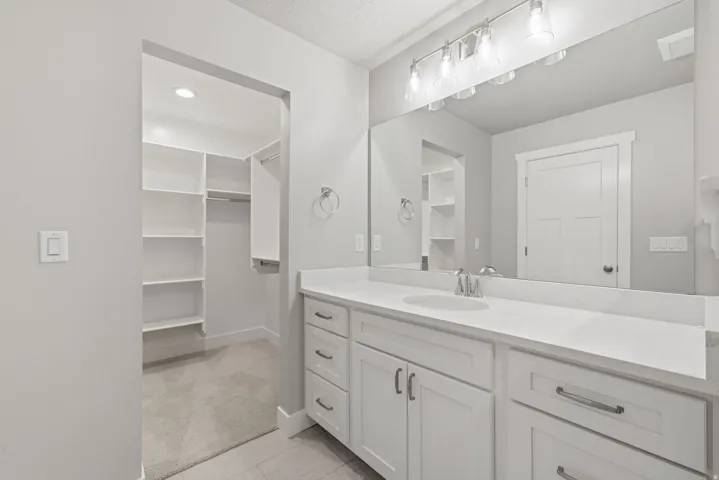 Vanity with an integrated sink, polished chrome faucet, and expansive mirror