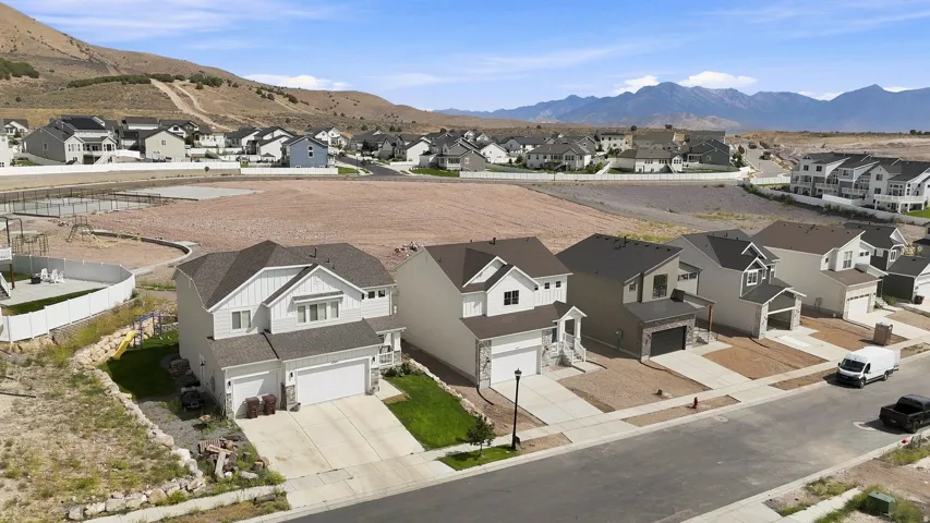 Contemporary residential streetscape with newly constructed homes, paved driveways, and mountain scenery
