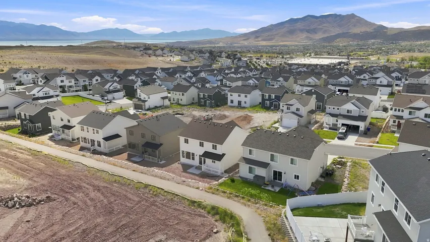 Residential neighborhood with diverse home exteriors, mountain backdrop, and distant body of water