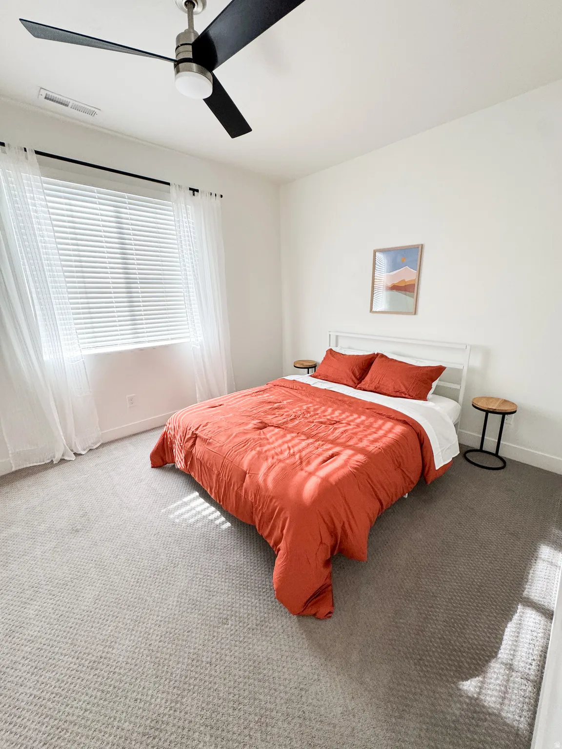 Neutral-toned wall-to-wall carpeting, white walls, and a window with blinds