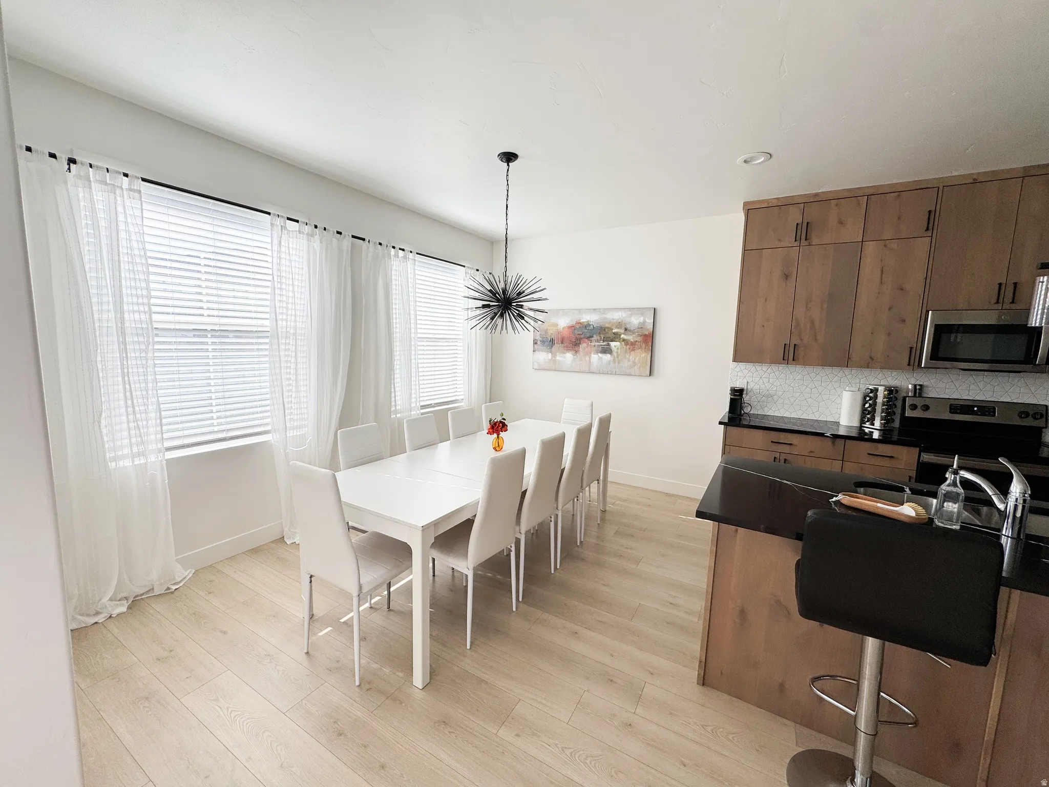 Light wood-finish flooring, recessed lighting, and a modern chandelier
