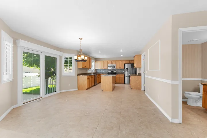 Tile flooring, stainless steel appliances, kitchen island, sliding glass door, and interior plantation shutters