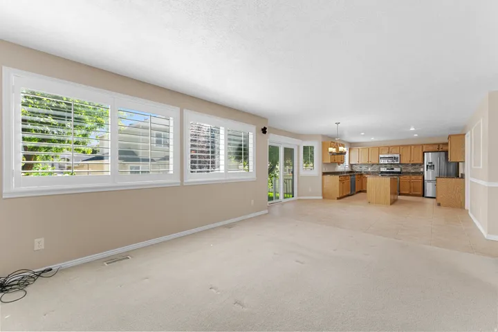 Open-concept living area with extensive windows featuring white plantation shutters