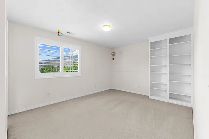 Built-in shelving, window with mountain backdrop, window with plantation shutters, ceiling-mounted light fixture, wall trim detail